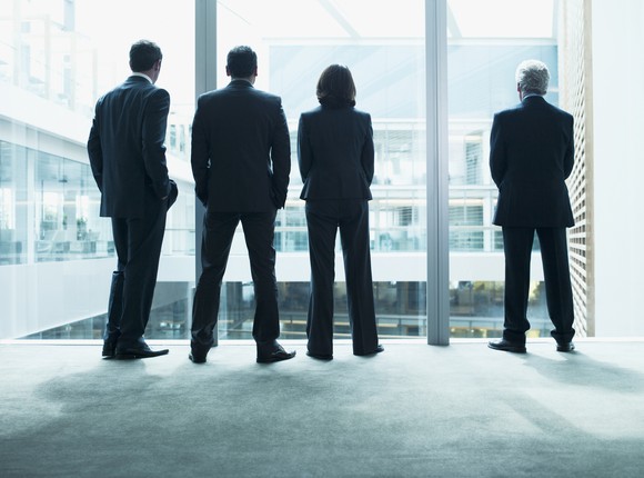Four executives in suits staring out a window
