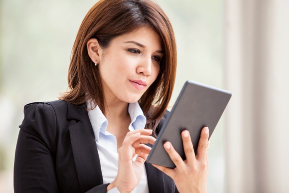 Young woman in a suit, focused on a tablet