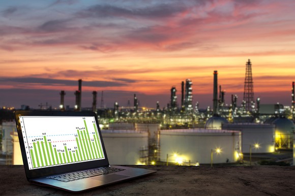 A laptop on a table with a petrochemical complex in the background.