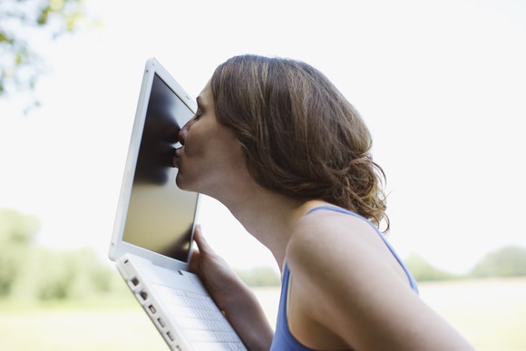 A woman kissing a laptop screen.