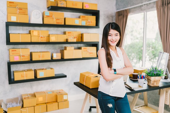 Young woman standing next to a shelf in her home office.