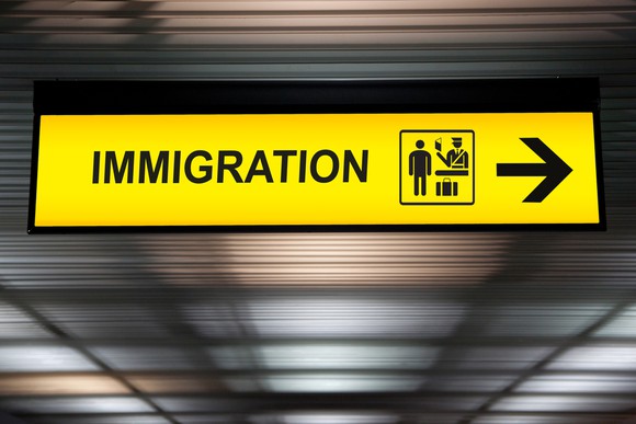 Yellow sign at airport that points to the right and says Immigration