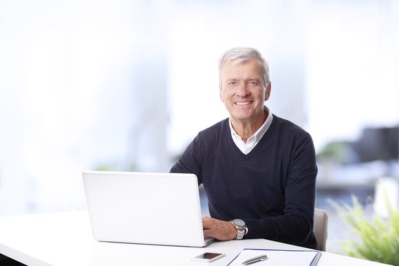 Smiling older man at a laptop.
