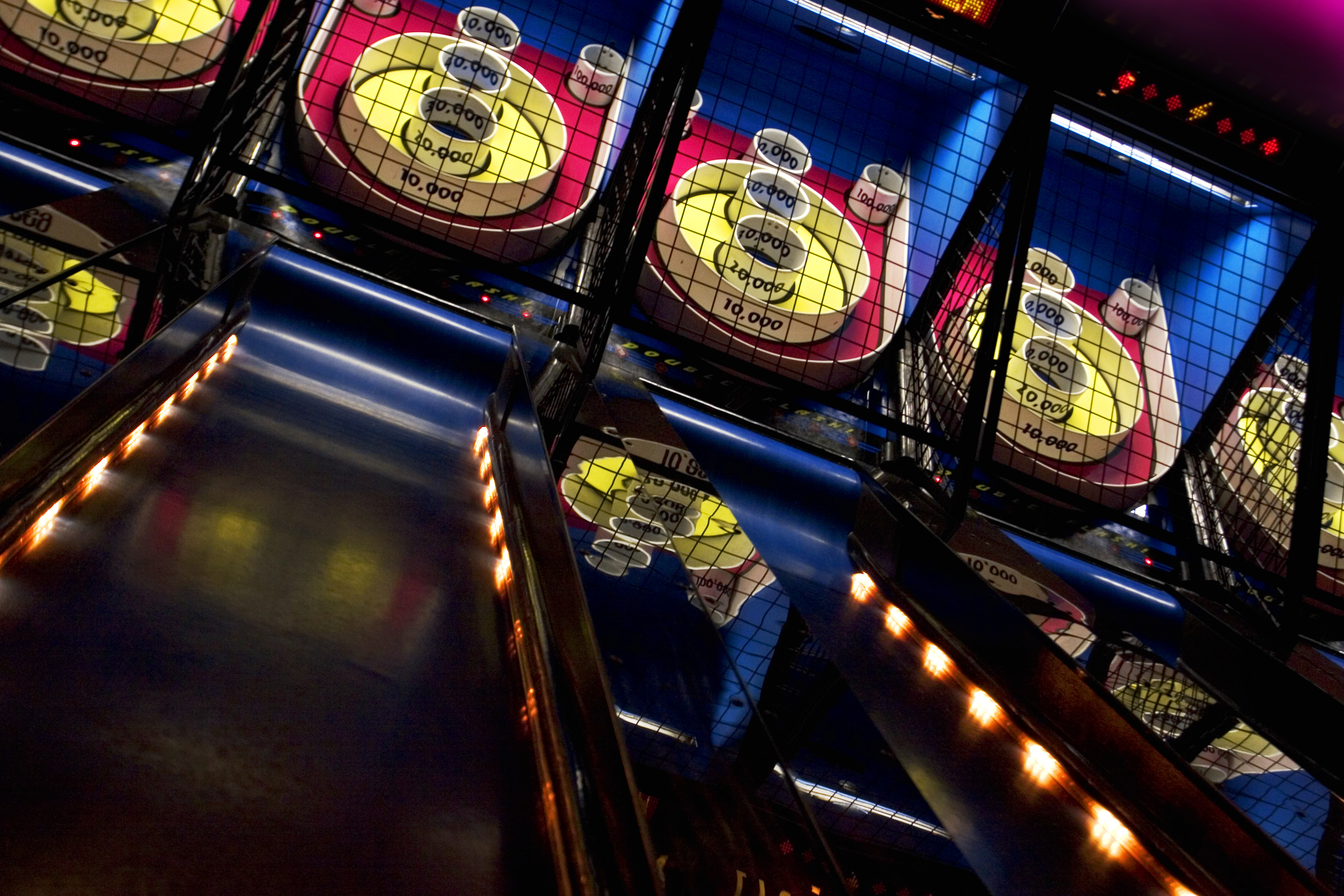 A row of games where the player rolls a ball up an inclined ramp launching it towards different holes.