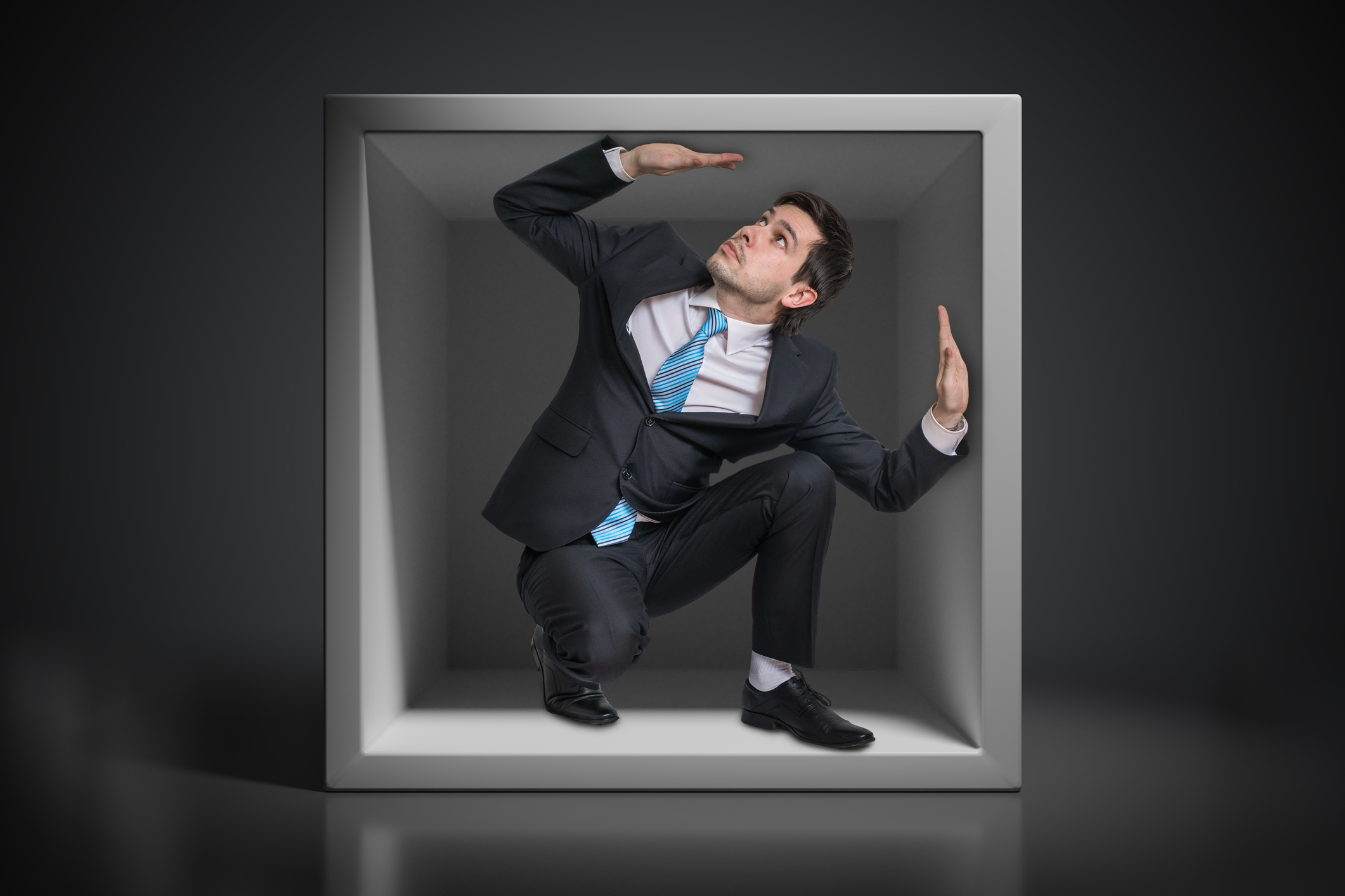 A man in a suit is trapped in a box.