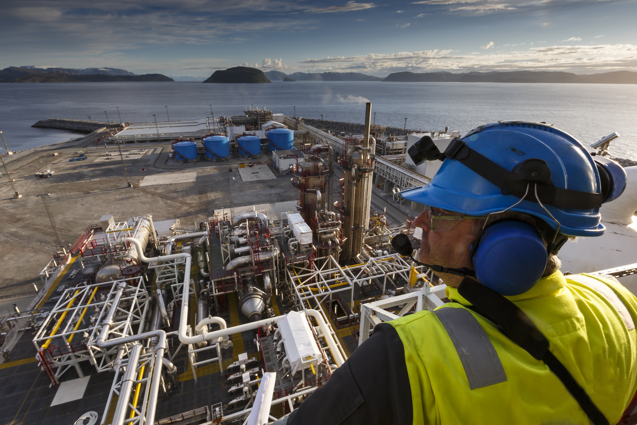 A man looking down over an oil processing plant