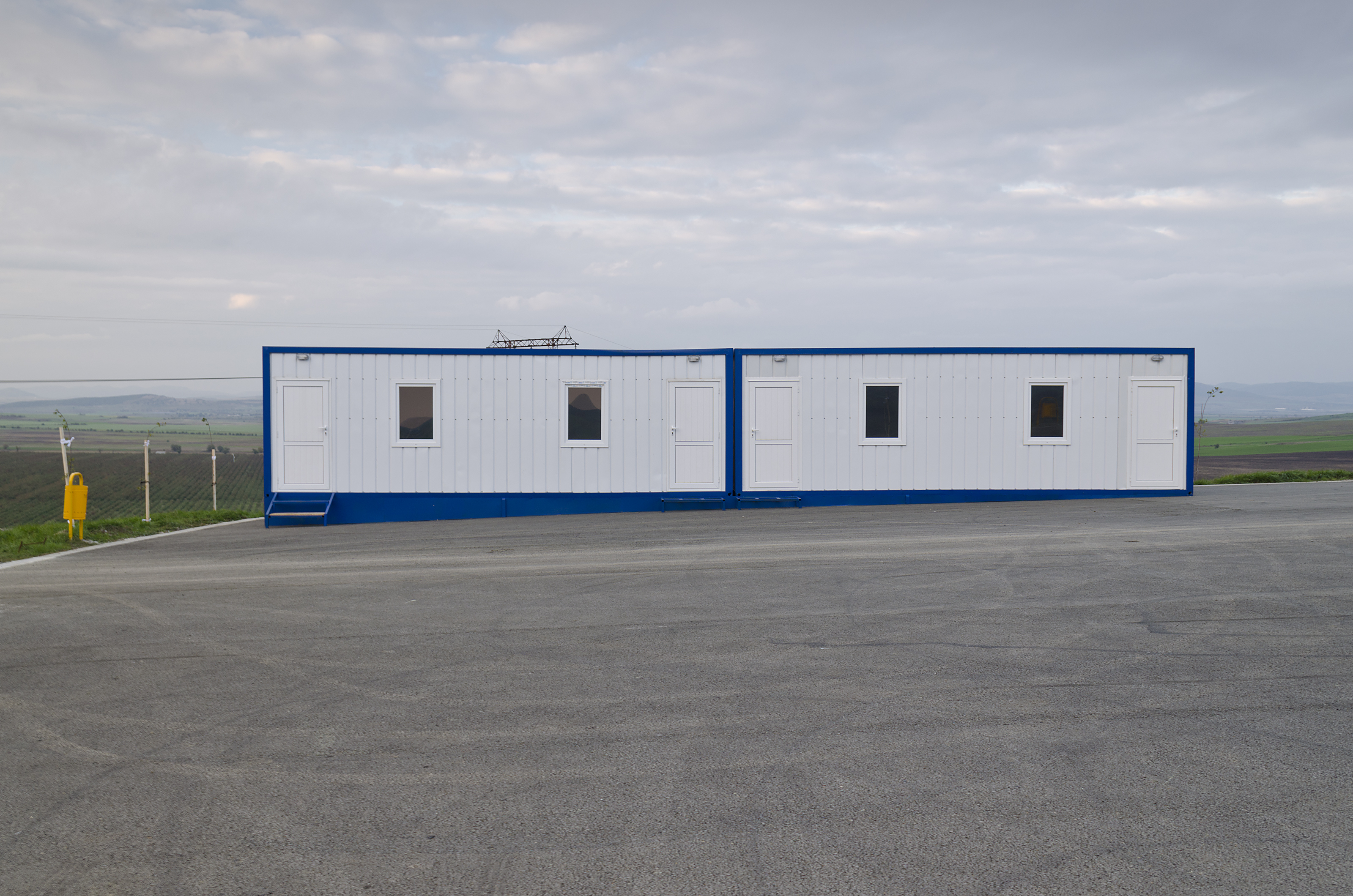 A white modular building with blue trim in a parking lot. 