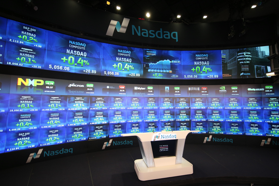 A television studio inside the Nasdaq exchange, with monitors bearing tickers prices in the background.