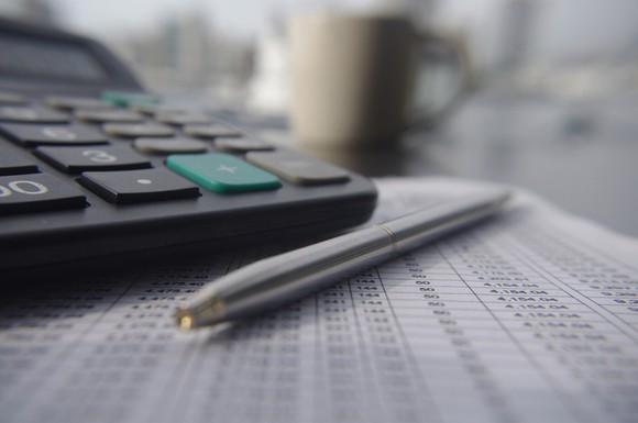 A calculator and a pen on a table.