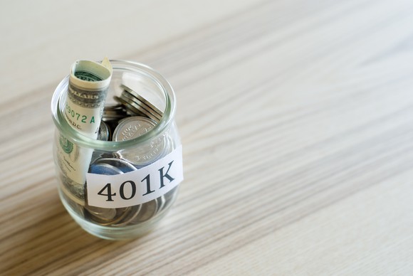 Glass jar with rolled-up bills and coins labeled 401K