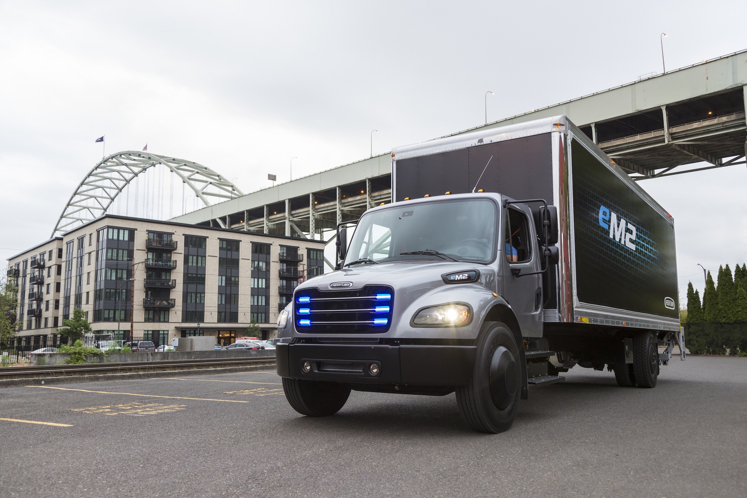 The Freightliner eM2 106, a battery-electric box truck with blue lights in its grille.