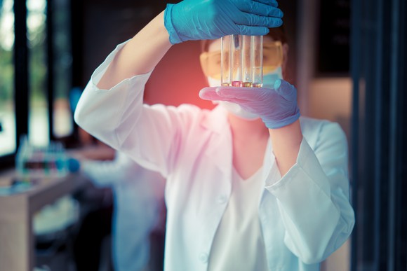 Person holding four test tubes in front or their face.