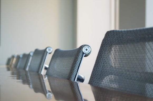 Office chairs pulled up in a row at a table.