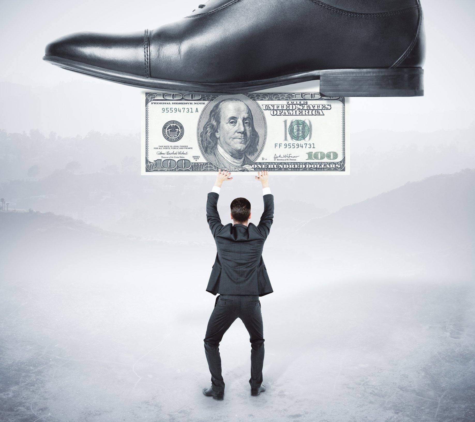 A miniature businessman attempting to hold up a hundred dollar bill which is being stepped on by a much larger shoe, representing big business. 
