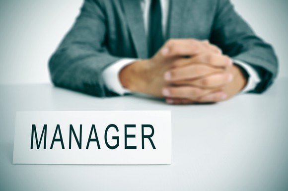 Man in suit with manager sign in front of him