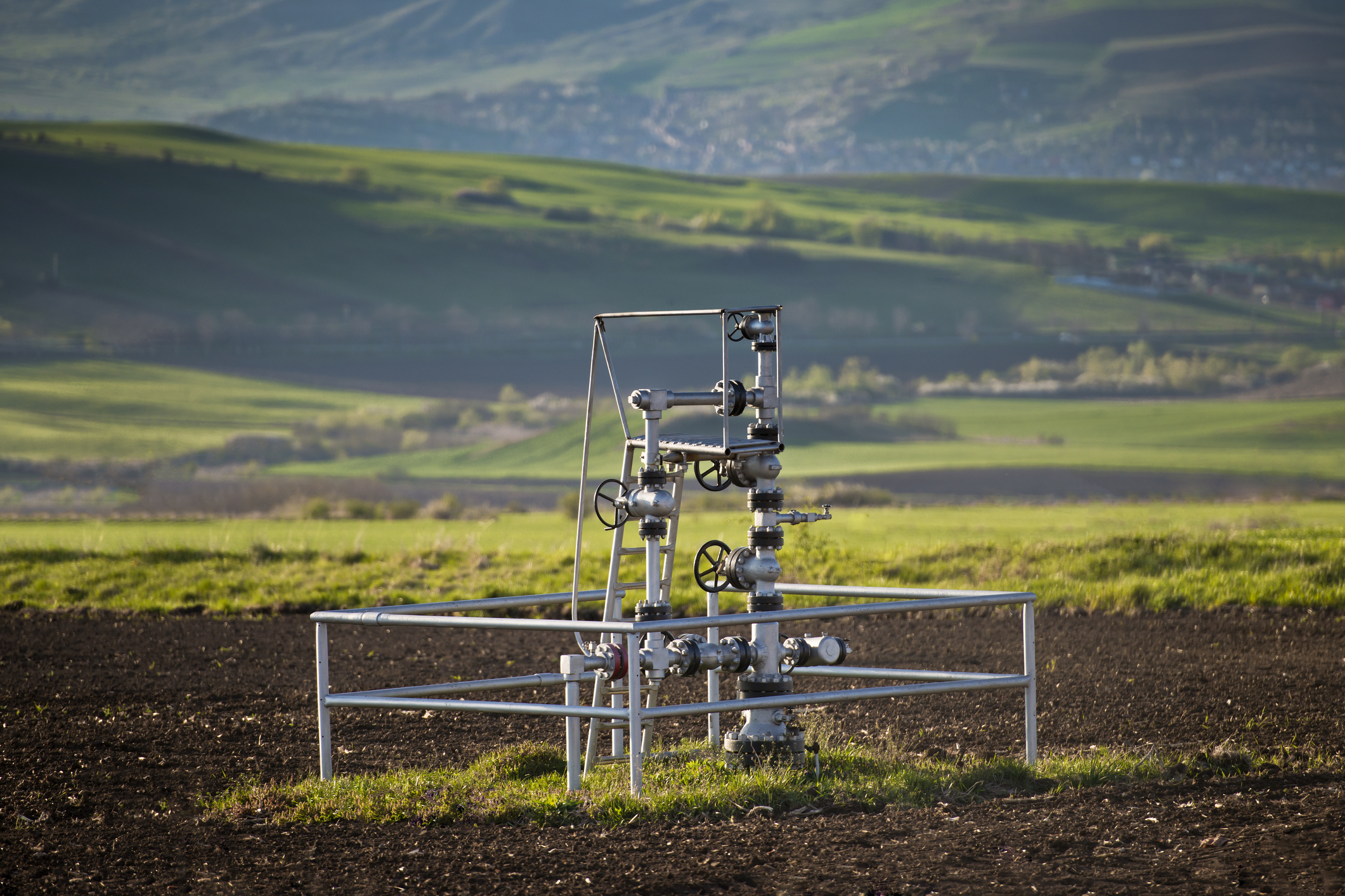 A natural gas wellhead in the middle of a field.