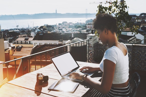 Woman typing on a laptop on a balcony