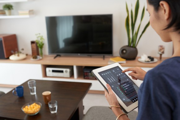 A woman using a smart-home application on a tablet.