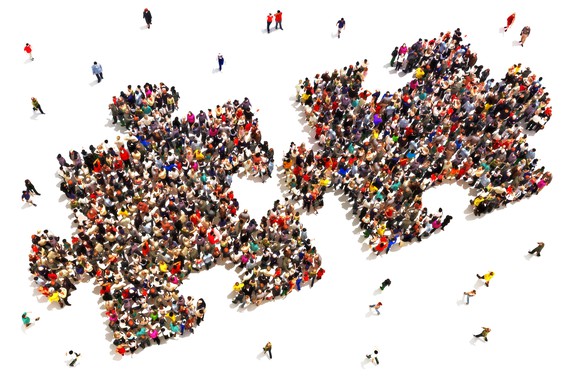 A crowd of several dozen people arranged to form two puzzle pieces, almost but not quite connected.