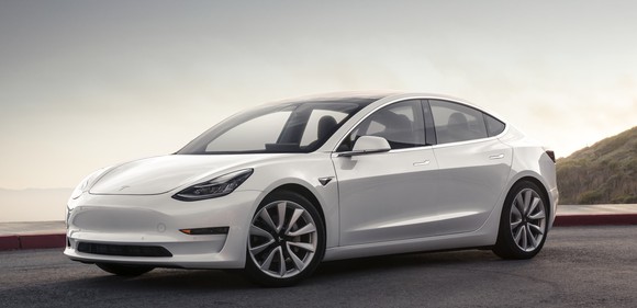 A white Tesla Model 3, a sleek compact luxury sedan