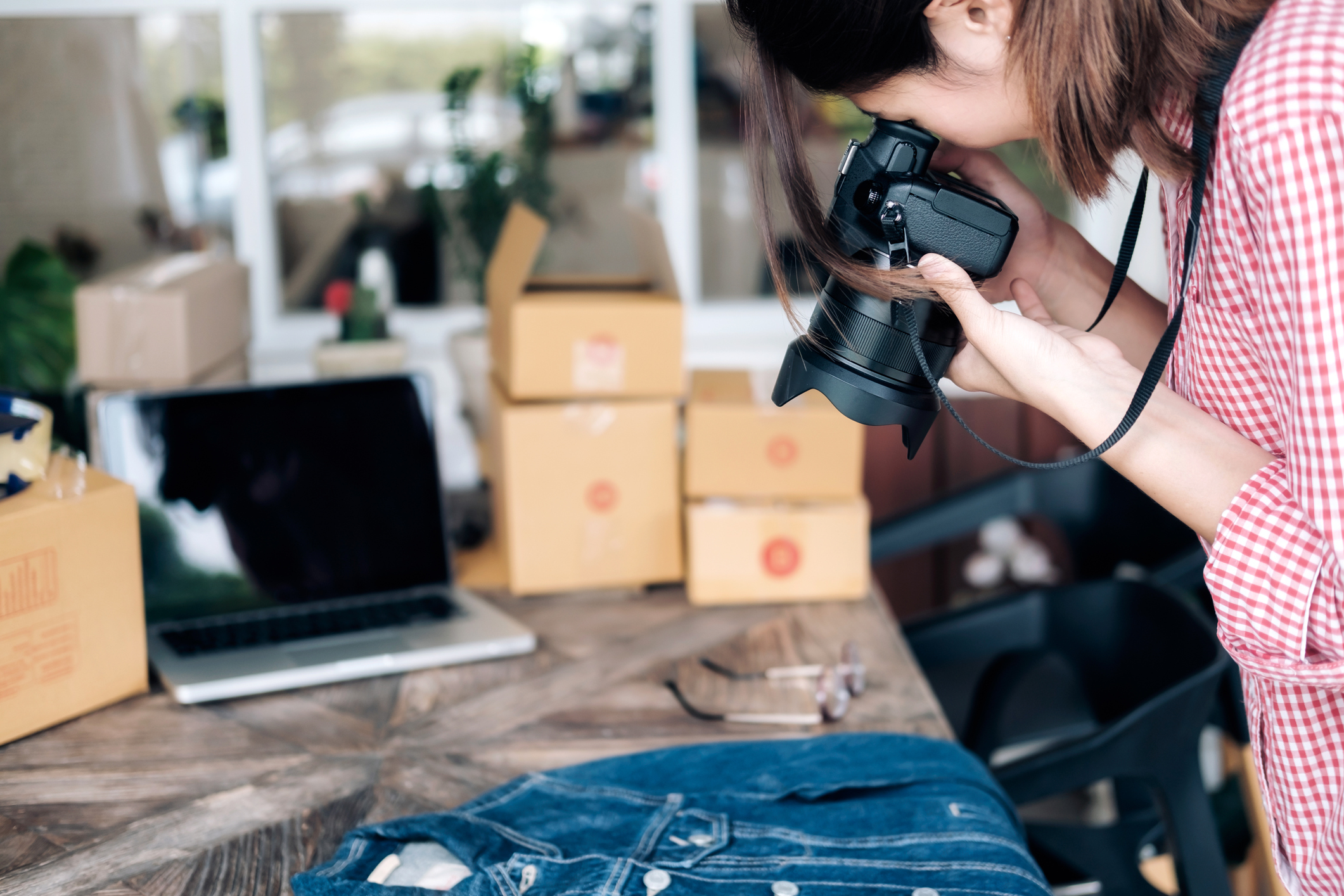 Online seller taking photograph of denim shirt before uploading image to website.