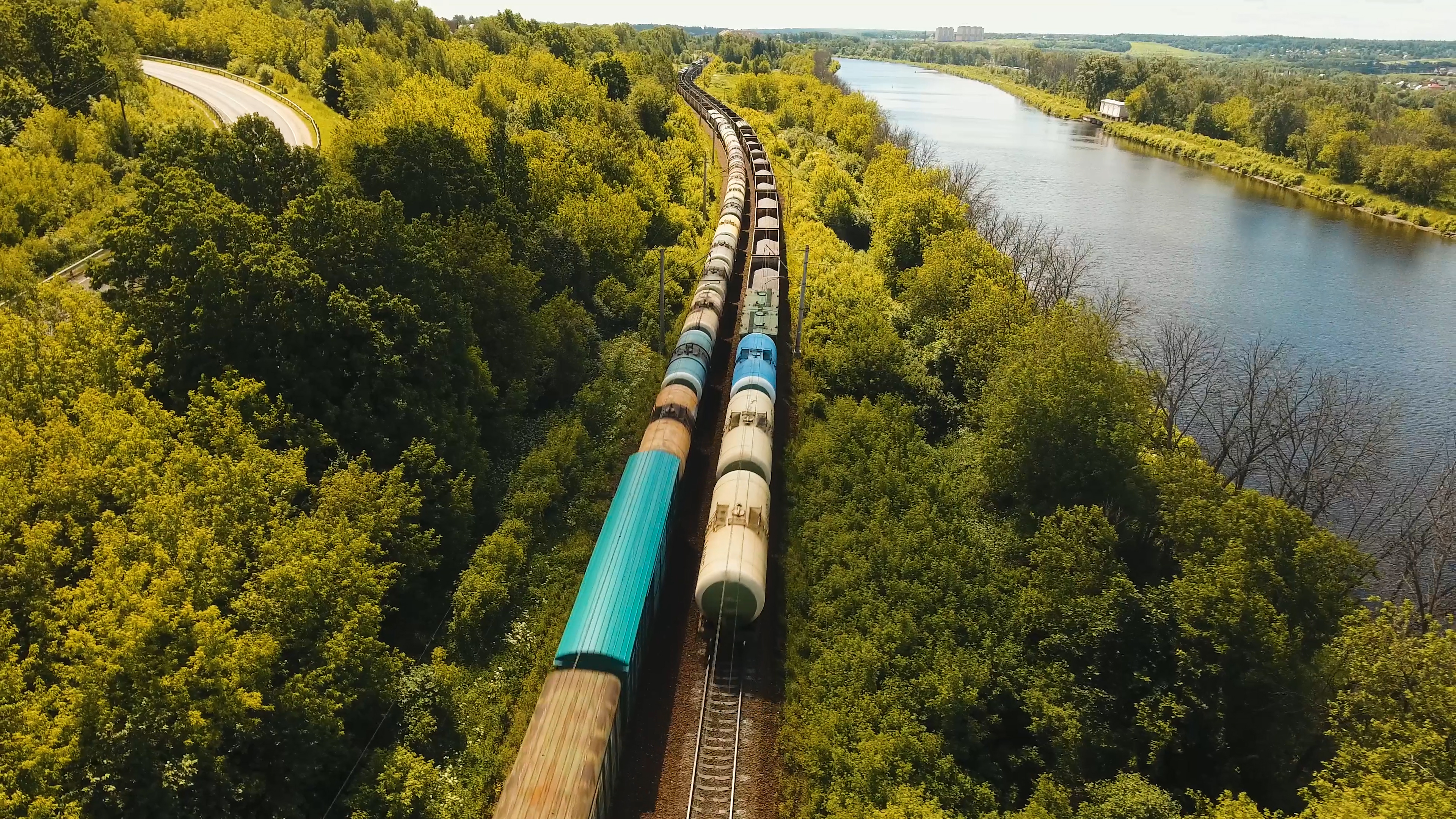 Freight train winding through countryside, beside a river.