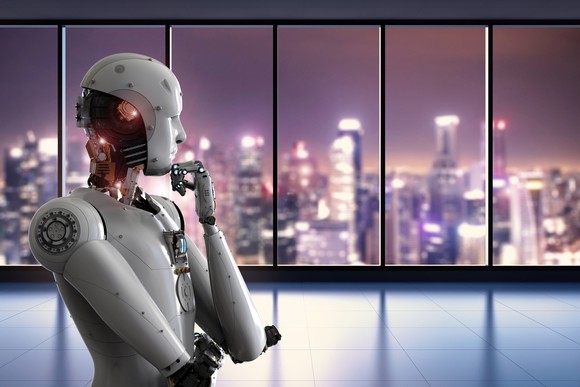 A robot shaped like a human looks toward the window, hand under chin.