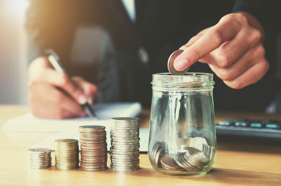 Someone counting coins and putting them in a jar.