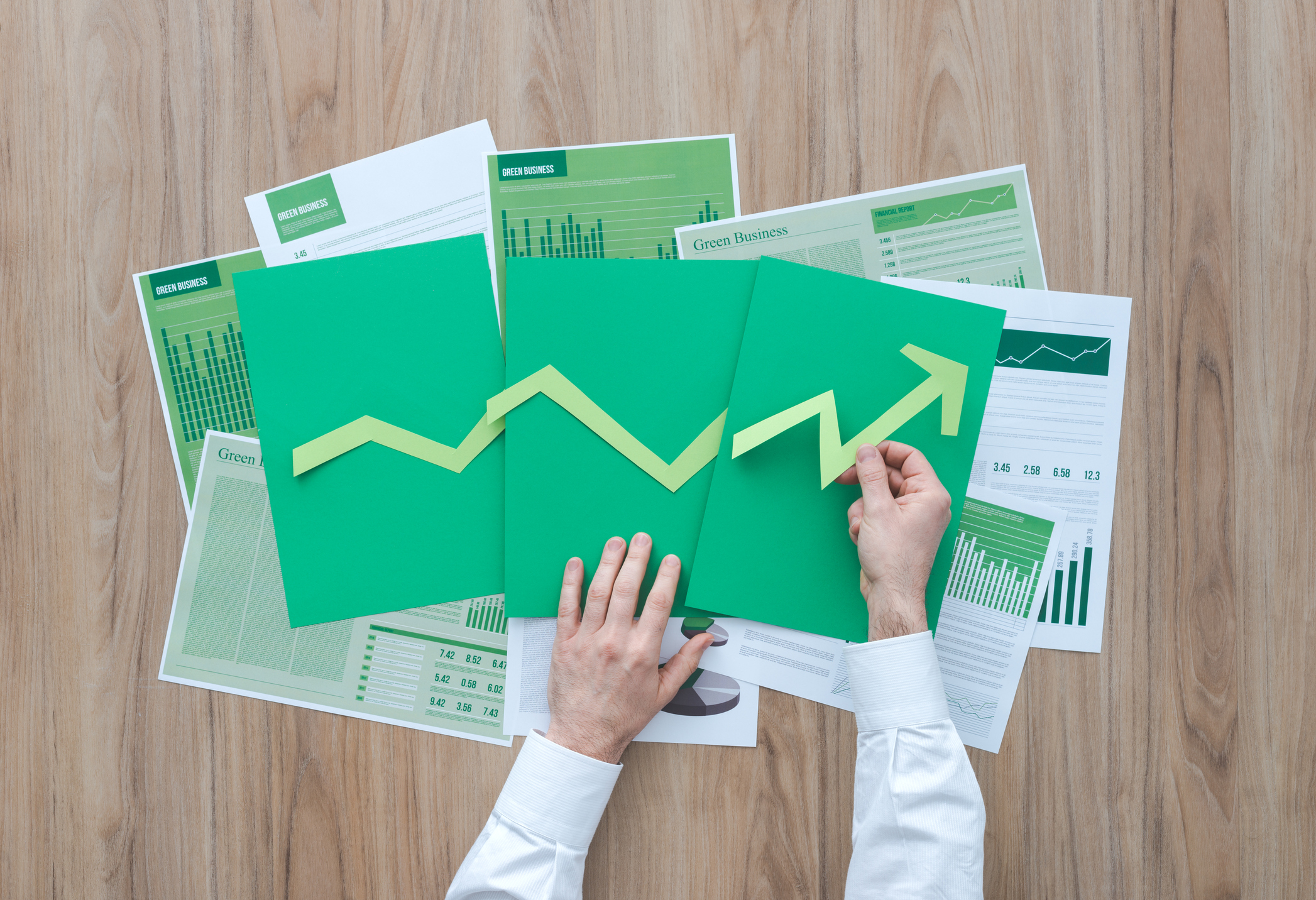 A person arranges cut up pieces of paper into an upwardly ascending arrow.