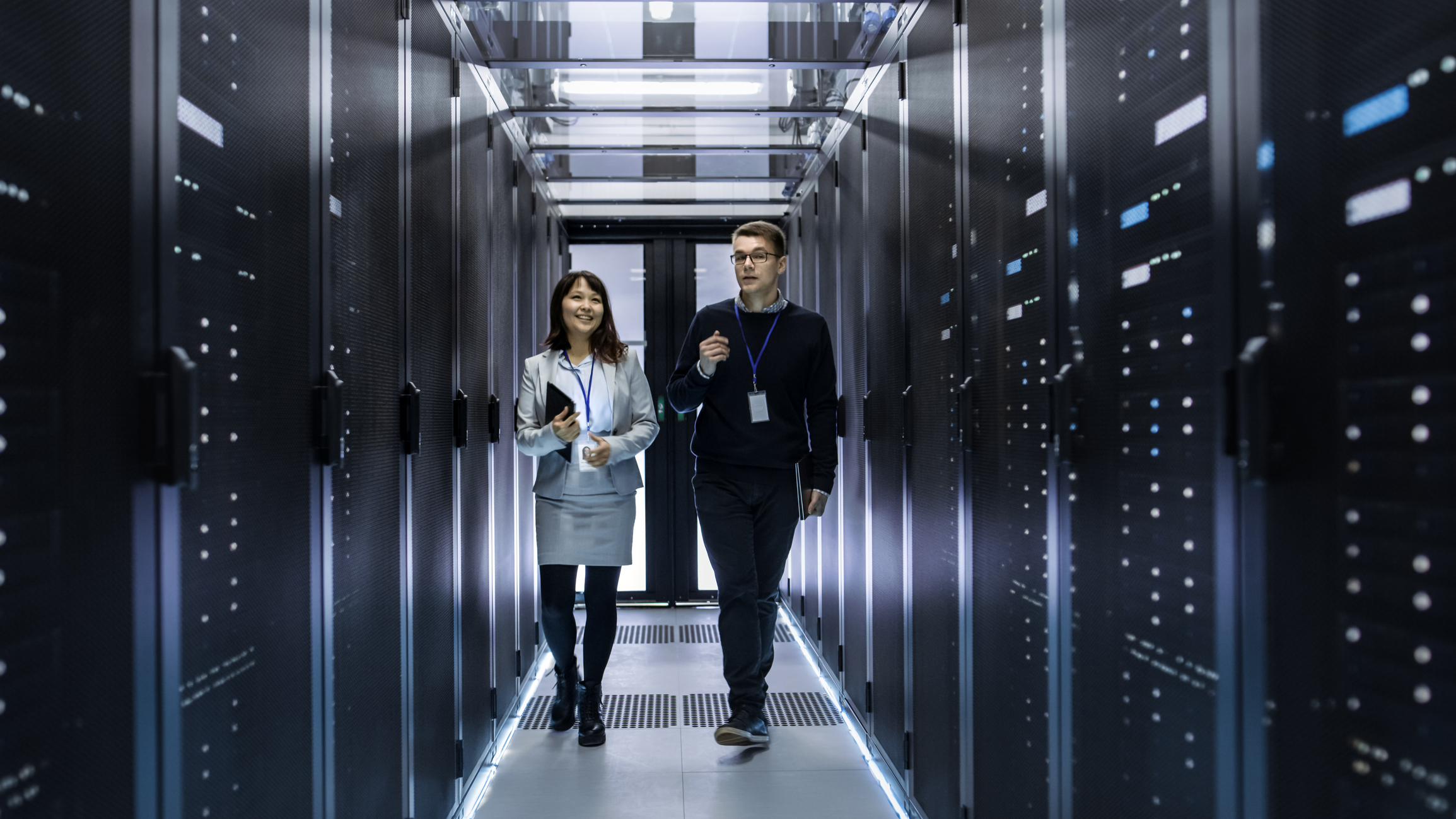 Two IT professionals walk through a data center.