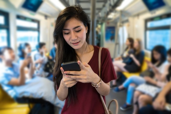 Asian woman using a smartphone on public transit.