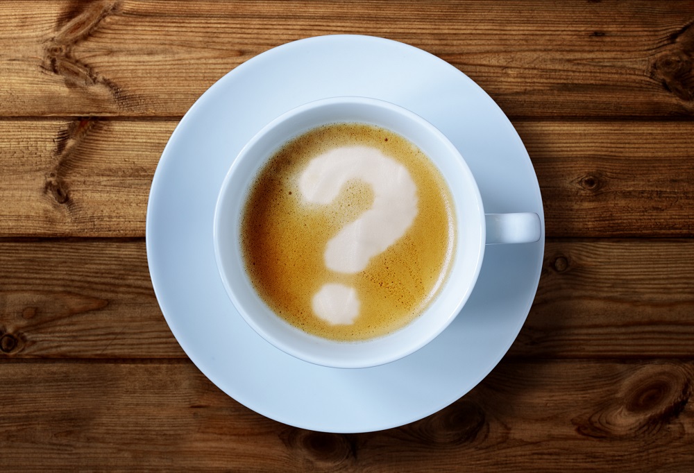 An overhead view of a coffee cup with a question mark in the froth.