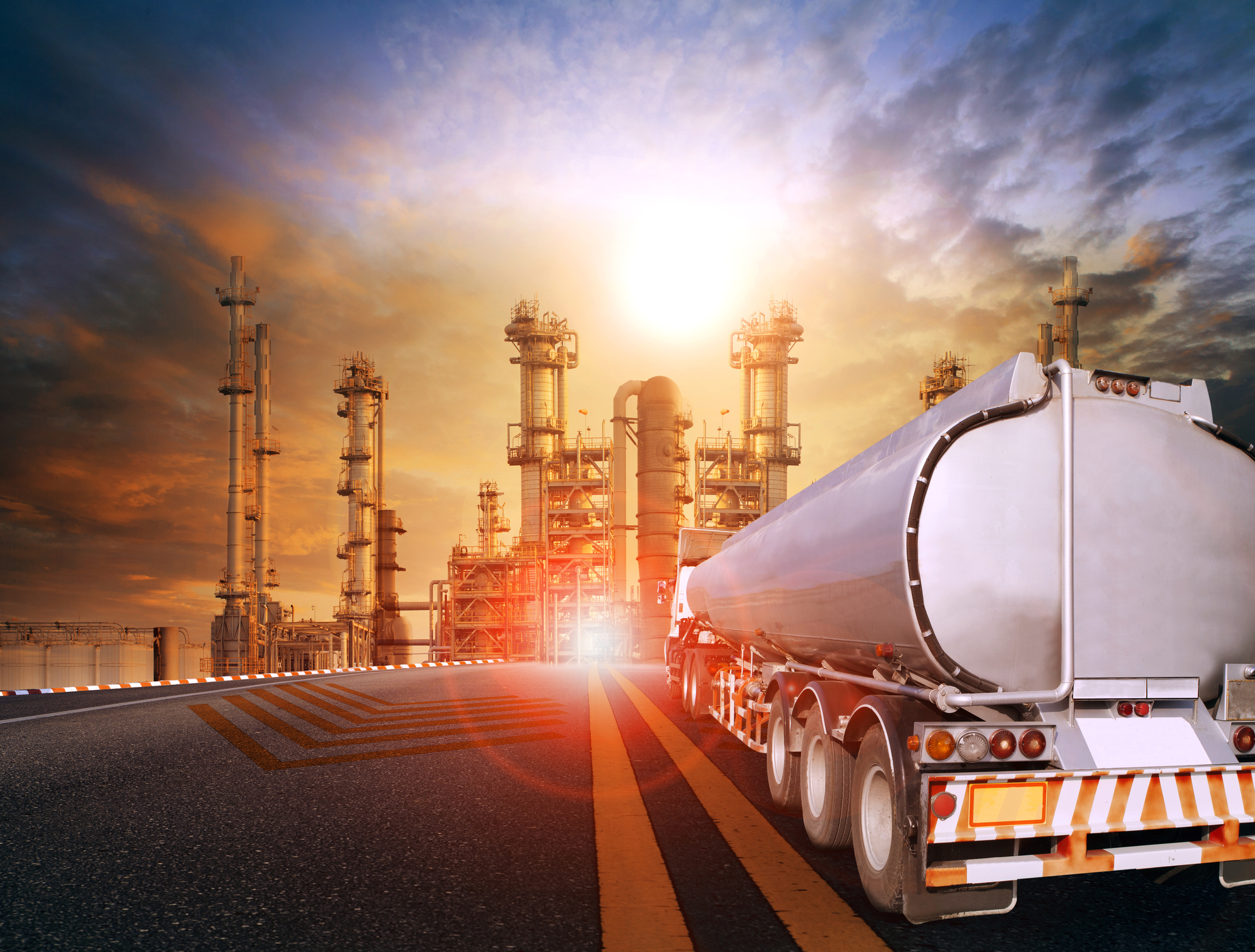 An oil and gas storage truck with an oil refinery in the background.