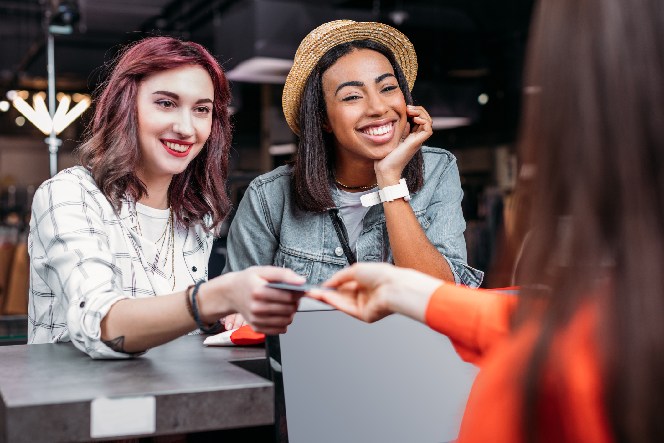 Two young women paying for purchases in a store with a credit card.