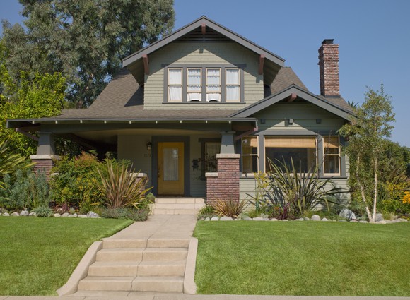 A gray-sided house and front lawn as seen from the street.
