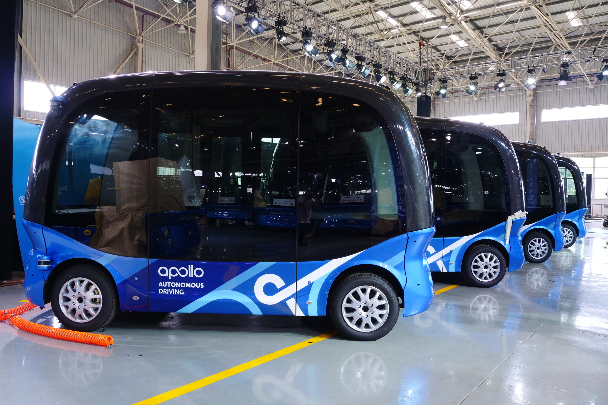 Several of Baidu's Apolong self-driving minibuses parked in large warehouse.