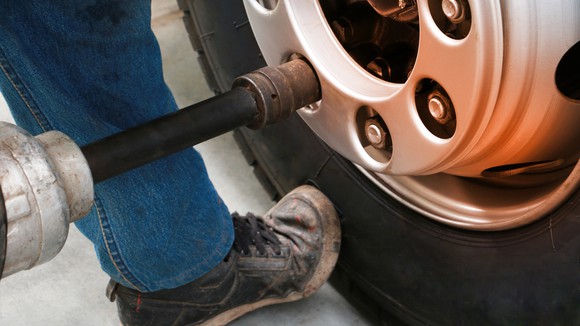 A person tightening nuts on a truck tire