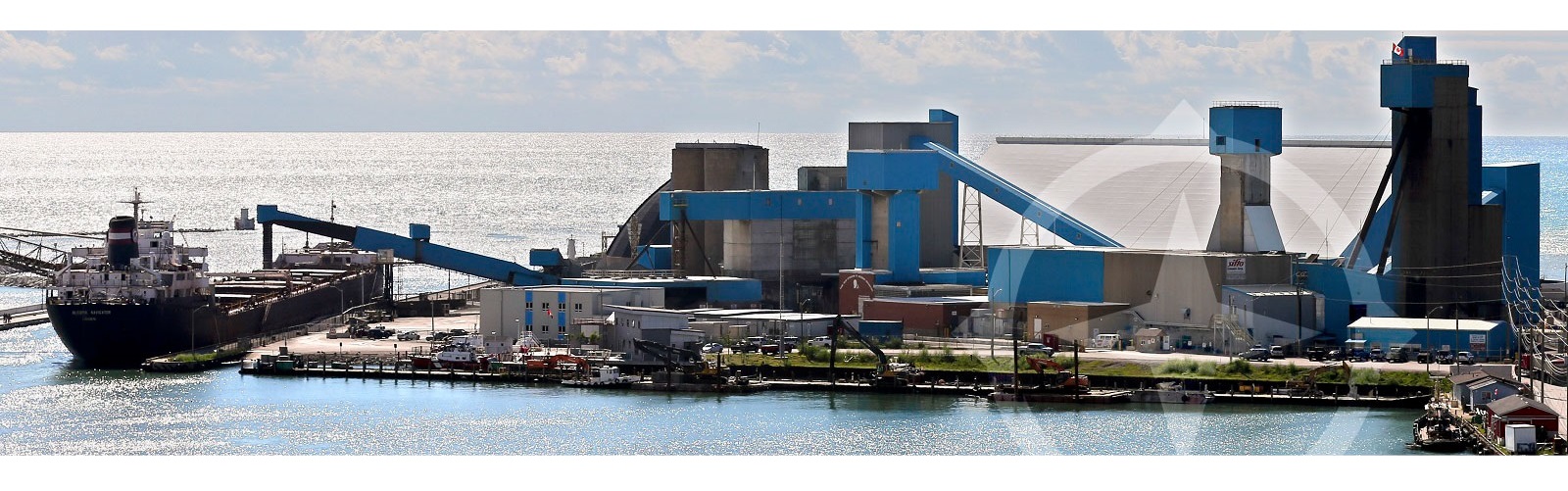 Processing plant and cargo loading facilities on a lake, with a ship taking on cargo.
