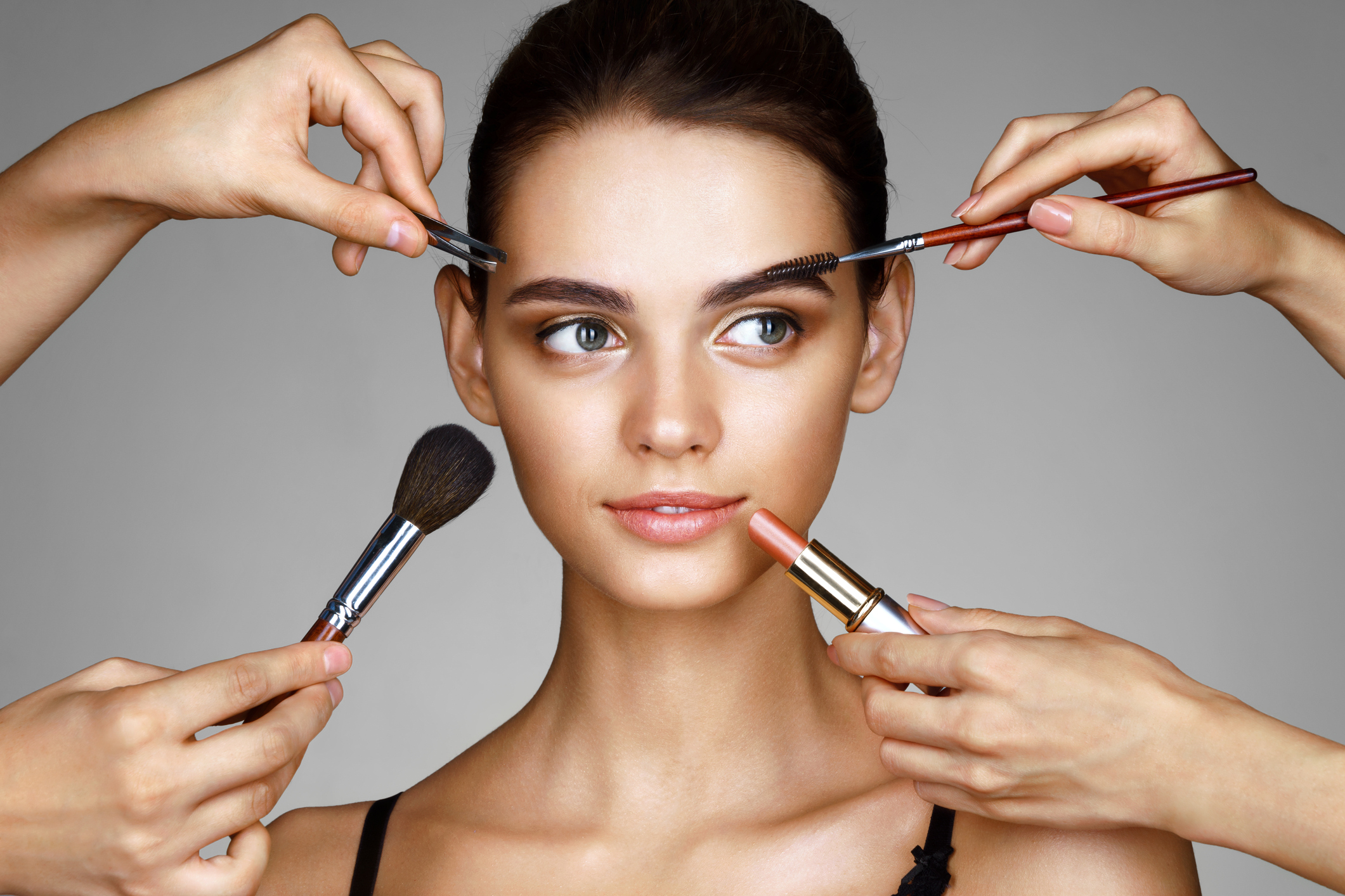 A woman having multiple cosmetic products applied to her face.