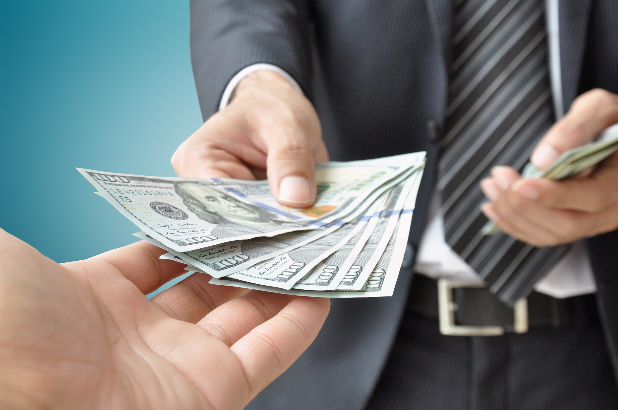 A person handing out $100 bills to another person