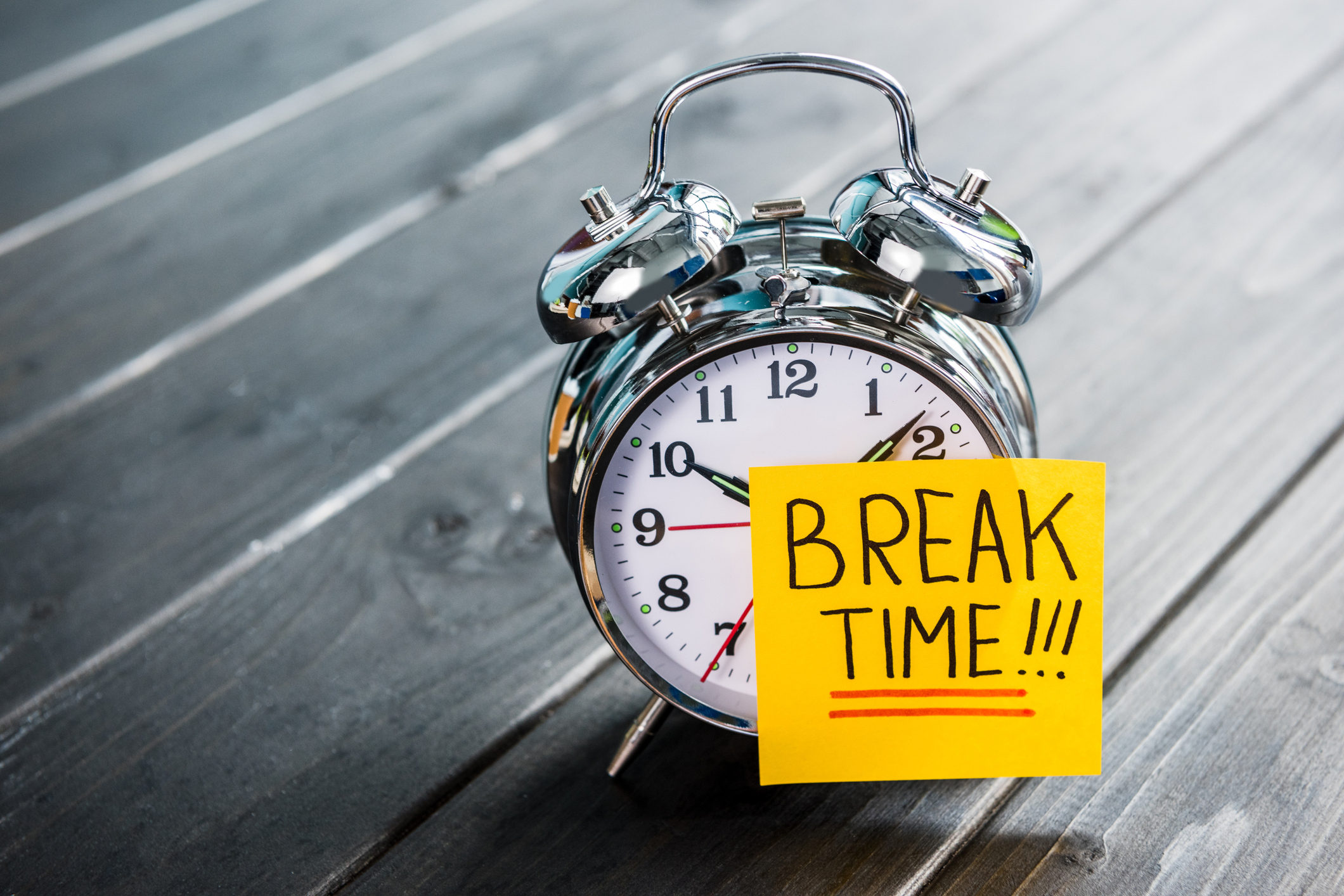 An alarm clock bearing a sticky note on which is written "Break time!"