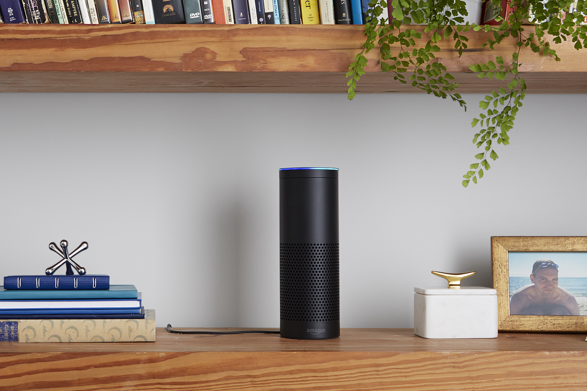 An Amazon Echo speaker on a bookshelf.