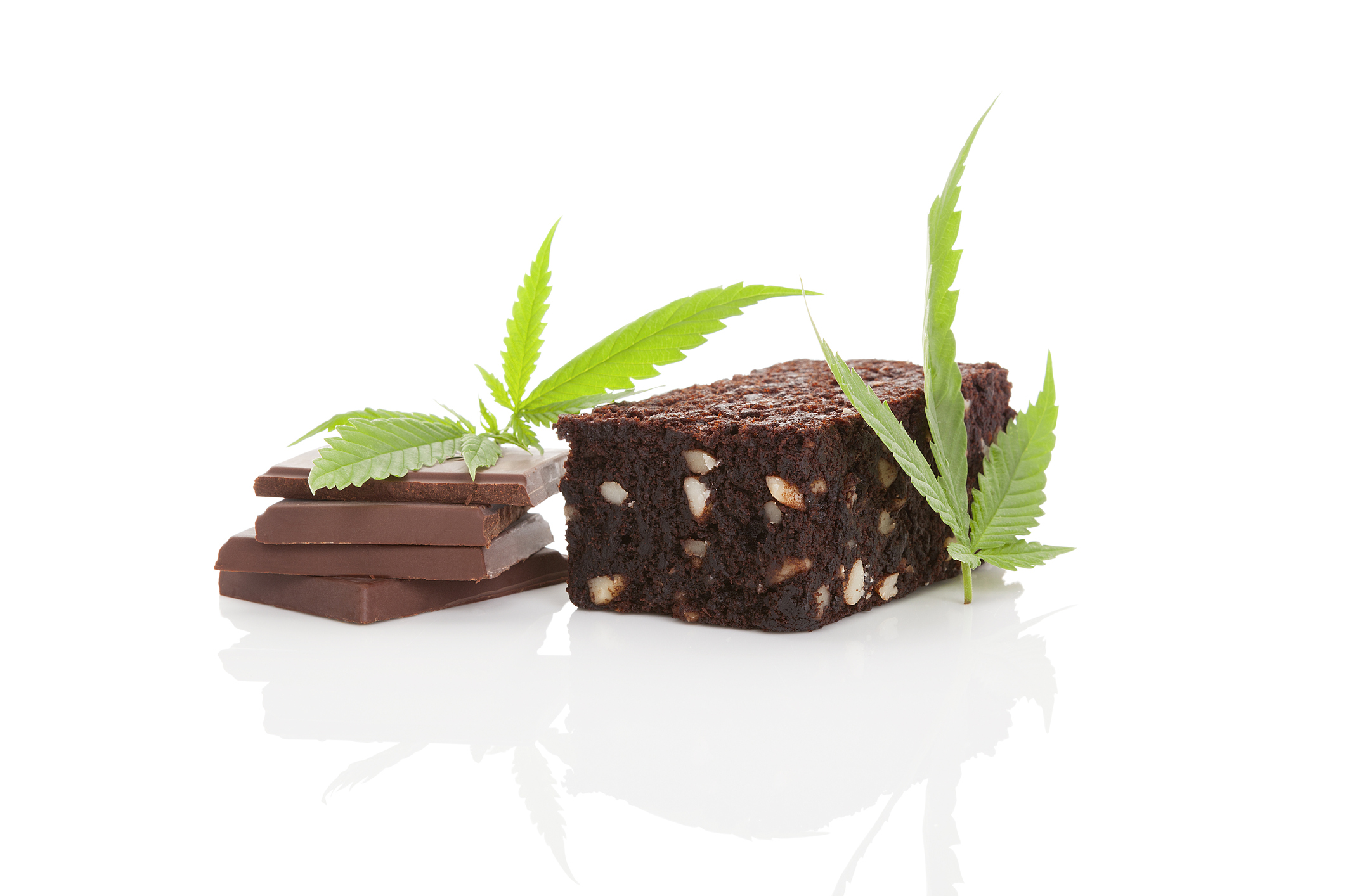 Cannabis leaves lying next to chocolate and a brownie. 