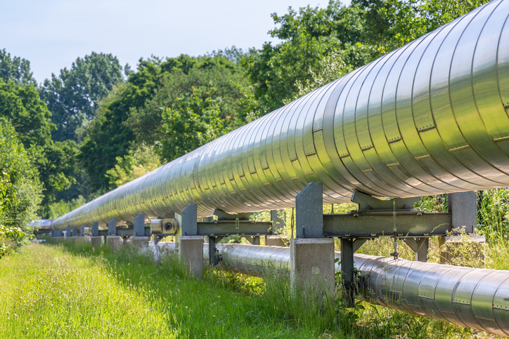 A natural gas pipeline running through a green forest.