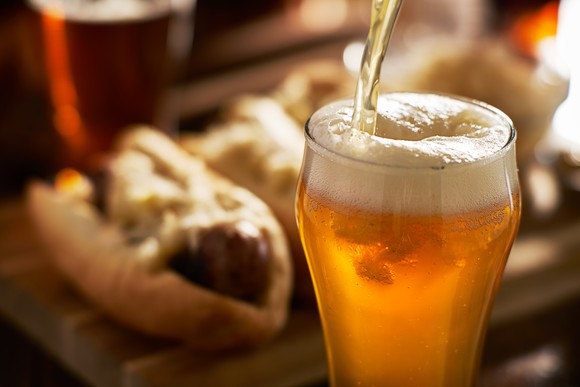 Draft beer pouring with hot dogs in the background.