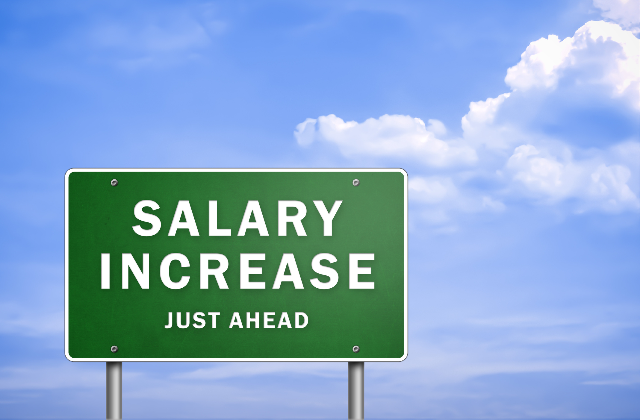 A green sign that says "salary increase just ahead" in front of blue skies.