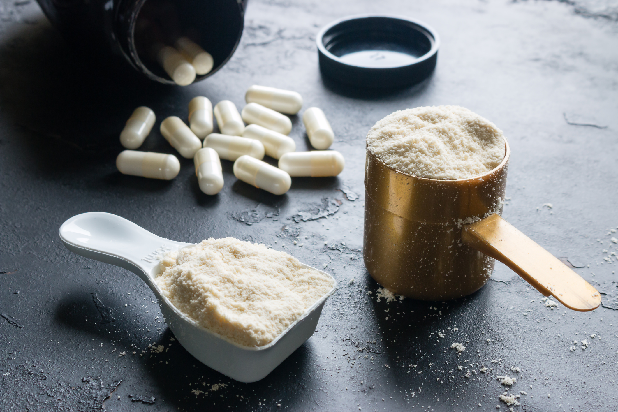 Supplements on a black table, with full measuring cups next to them.