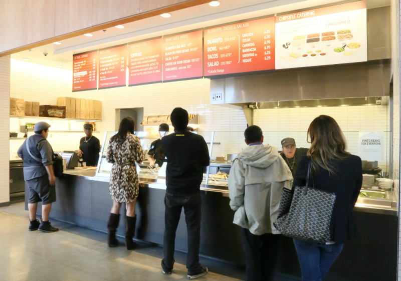 Customers stand in line at a Chipotle.