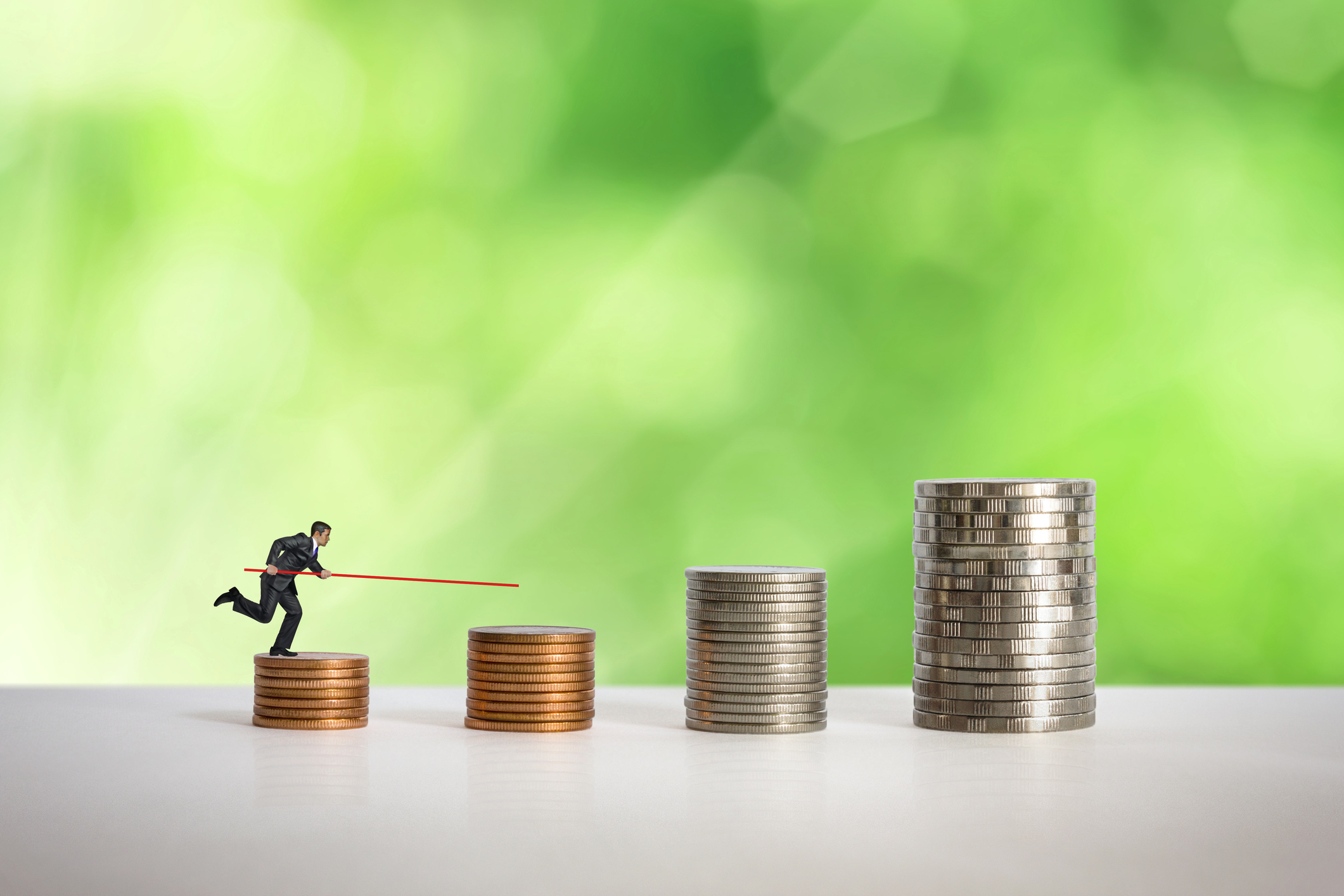 Mini-doll pole vaulter working up across a series of stacked coins.
