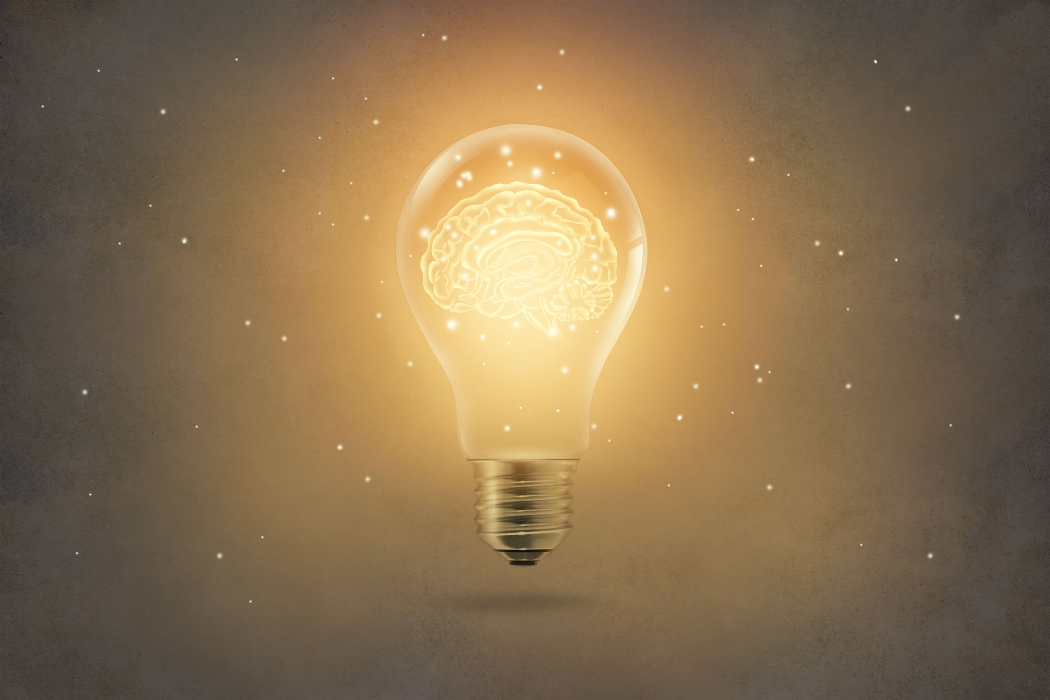 Golden brain glowing inside a light bulb on paper texture background